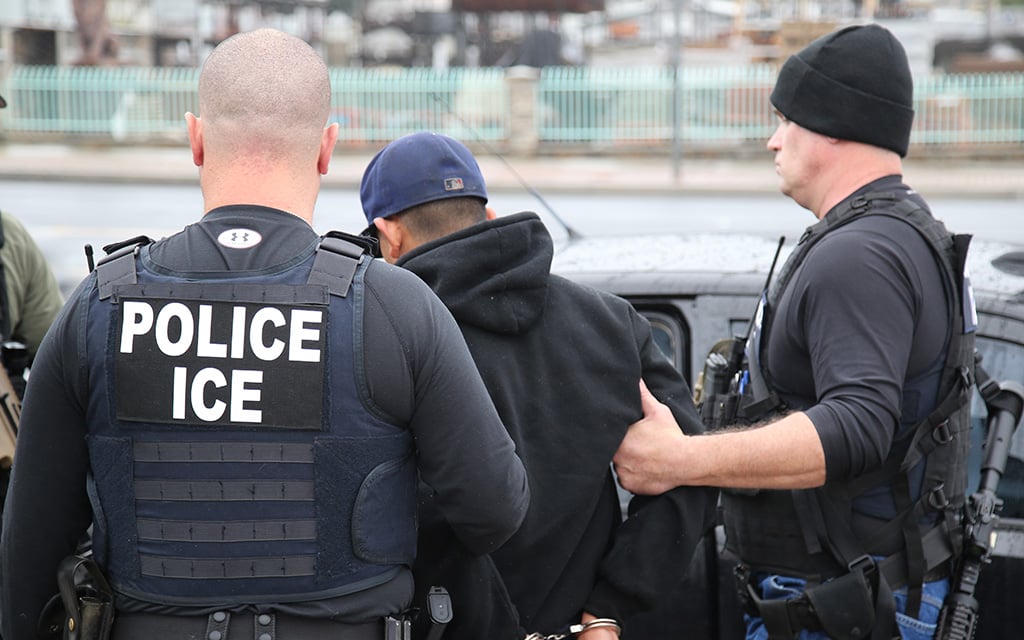 ICE officers detaining a man in urban area during enforcement