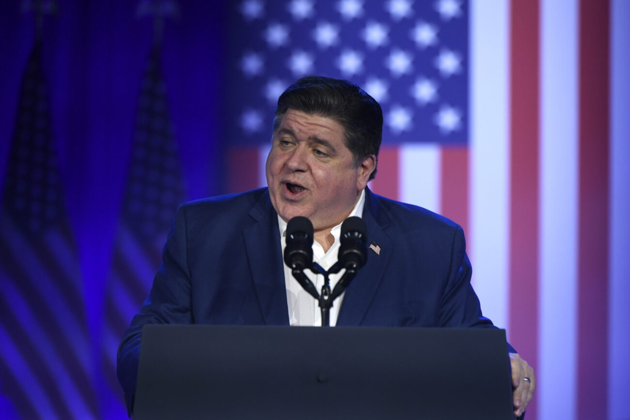 Man speaking at podium with USA flag background.