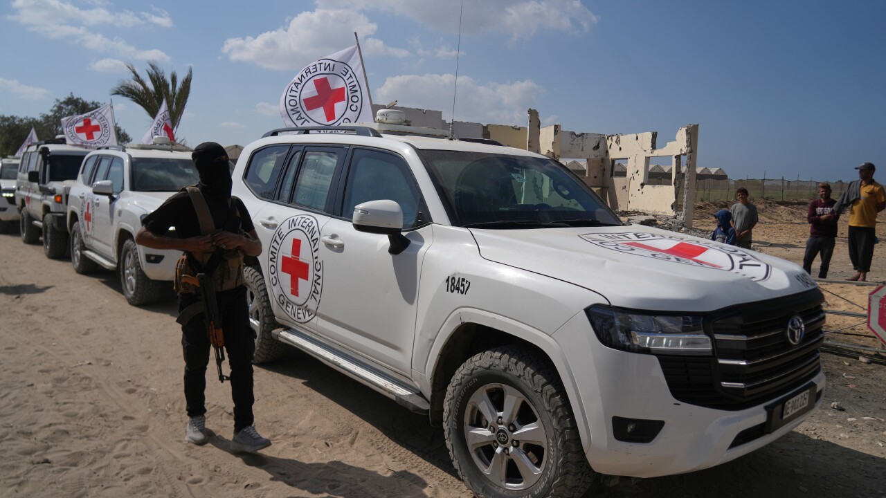 Red Cross vehicles in a sandy area with people nearby